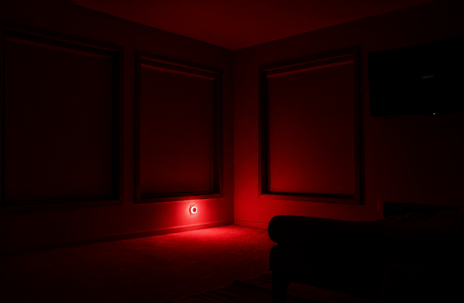 Room with blackout shades drawn and the night light glowing red on the wall